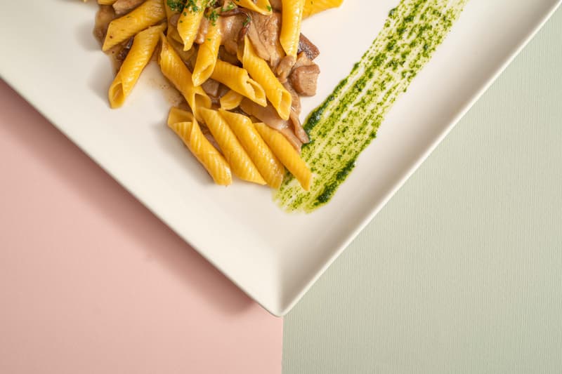 Piatto di pasta con una salsa verde alle erbe su un piatto bianco moderno