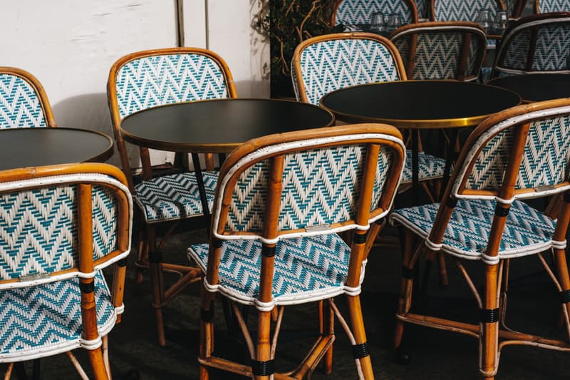 Rattan bistro chairs and small round tables lined up on a terrace