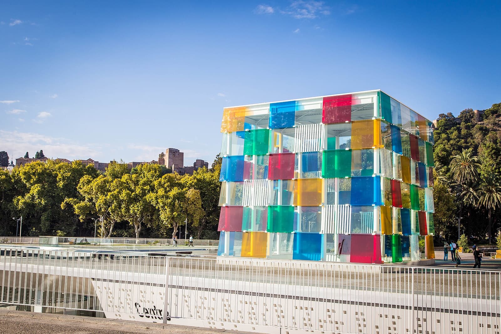 Bunter Glaswürfel des Centre Pompidou Málaga an der Hafenpromenade unter blauem Himmel