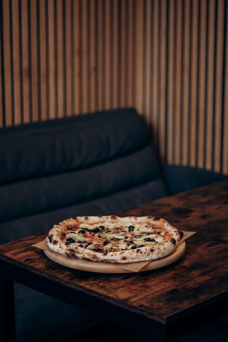 Una pizza napolitana al horno de leña servida en una mesa de madera en un restaurante italiano