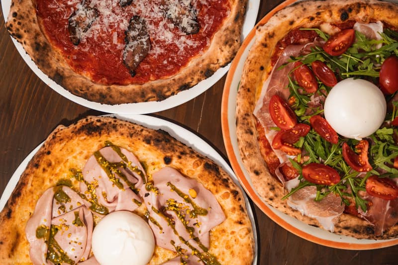 Tres pizzas napolitanas con burrata, mortadela y jamón sobre una mesa de madera