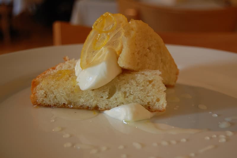 Fetta di torta all'olio d'oliva con panna e una fettina di limone candito nel piatto