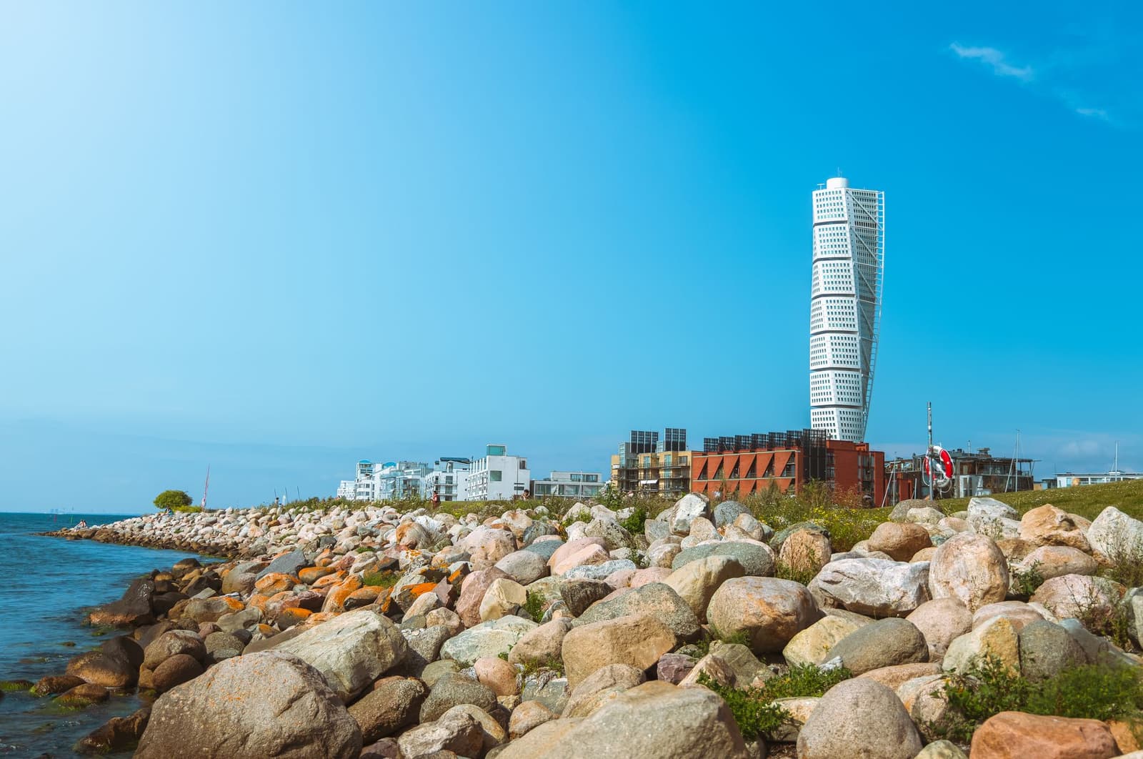 Der Wolkenkratzer Turning Torso an Malmös felsiger Küste unter klarem blauen Himmel