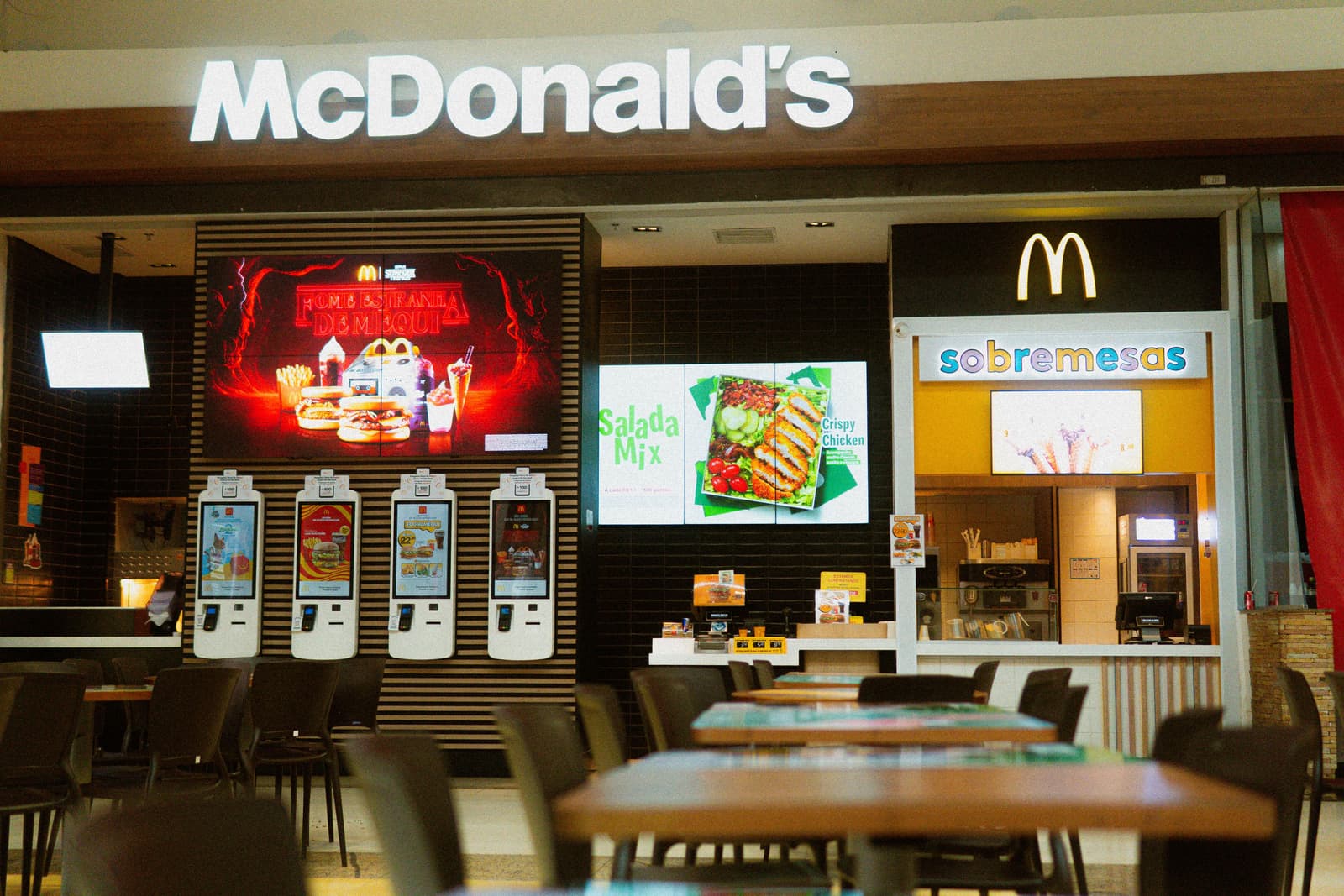 McDonald's-Filiale mit beleuchtetem Schild und digitalen Bestellkiosken
