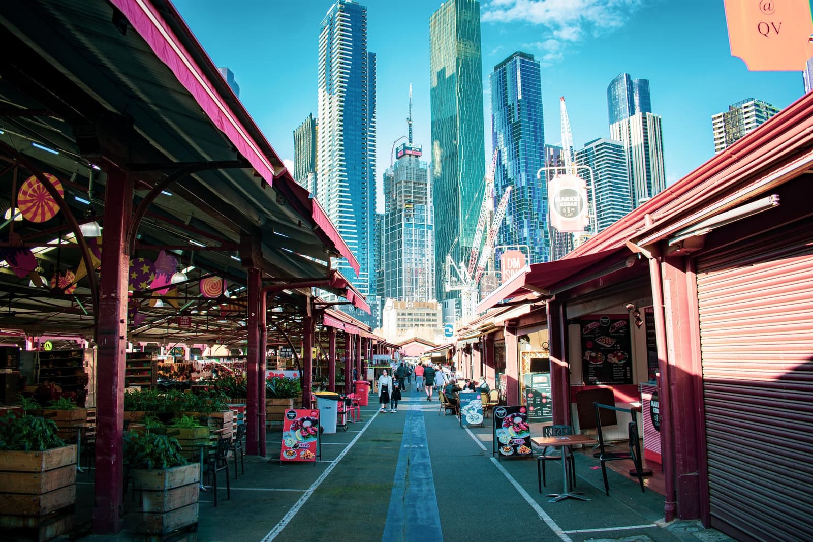 Bancarelle di cibo al Queen Victoria Market con i grattacieli di Melbourne sullo sfondo