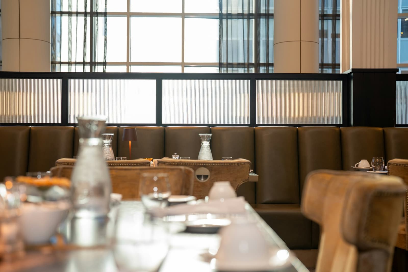 Salle de restaurant moderne avec banquettes en cuir et grandes fenêtres