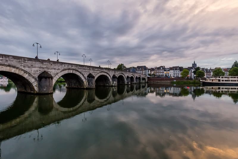 Archi in pietra del ponte San Servazio riflessi nella Mosa al tramonto a Maastricht