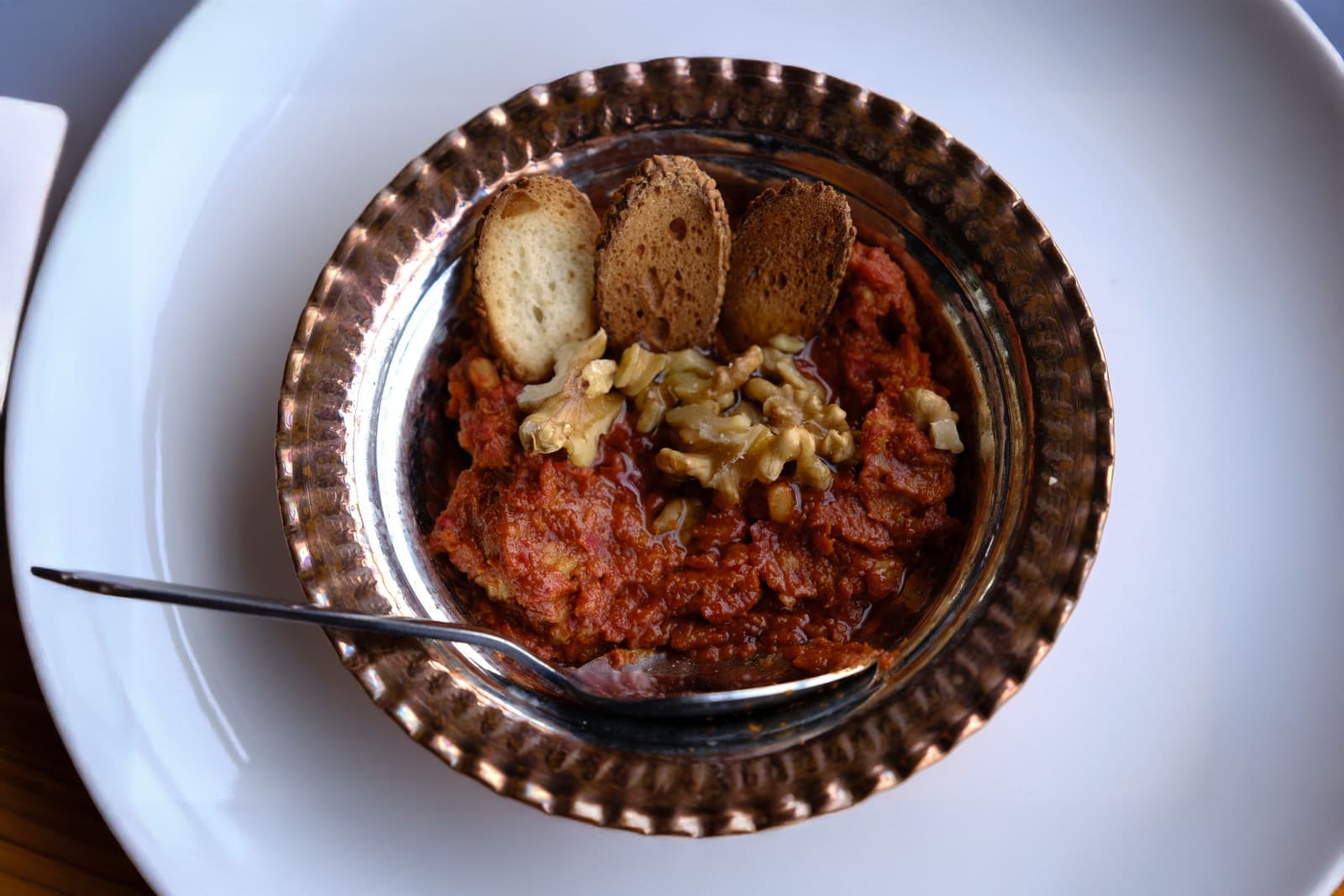 Muhammara di peperoni e noci in una ciotola di rame con pane tostato