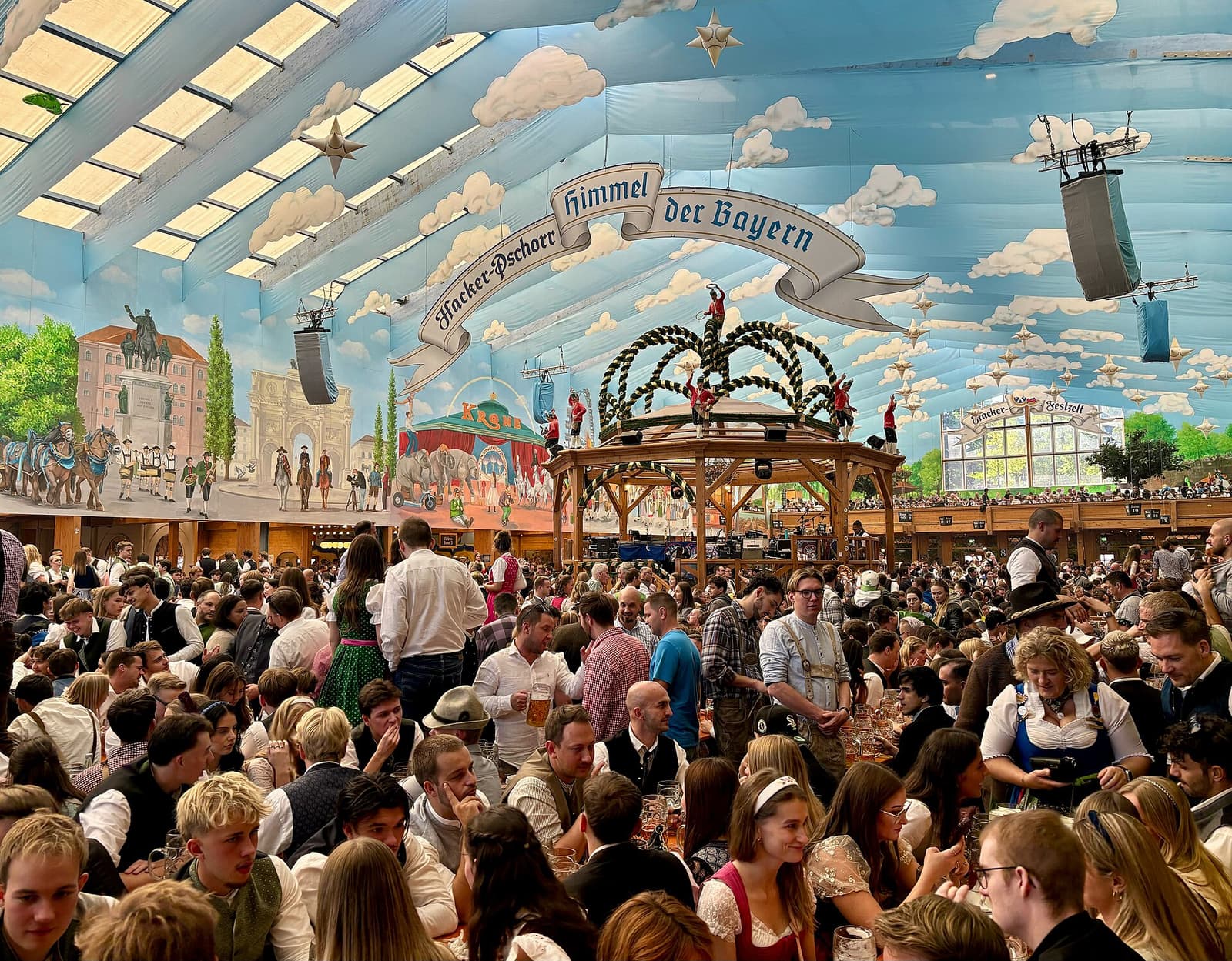 Tente à bière bondée à l'Oktoberfest de Munich sous un plafond peint en ciel bleu