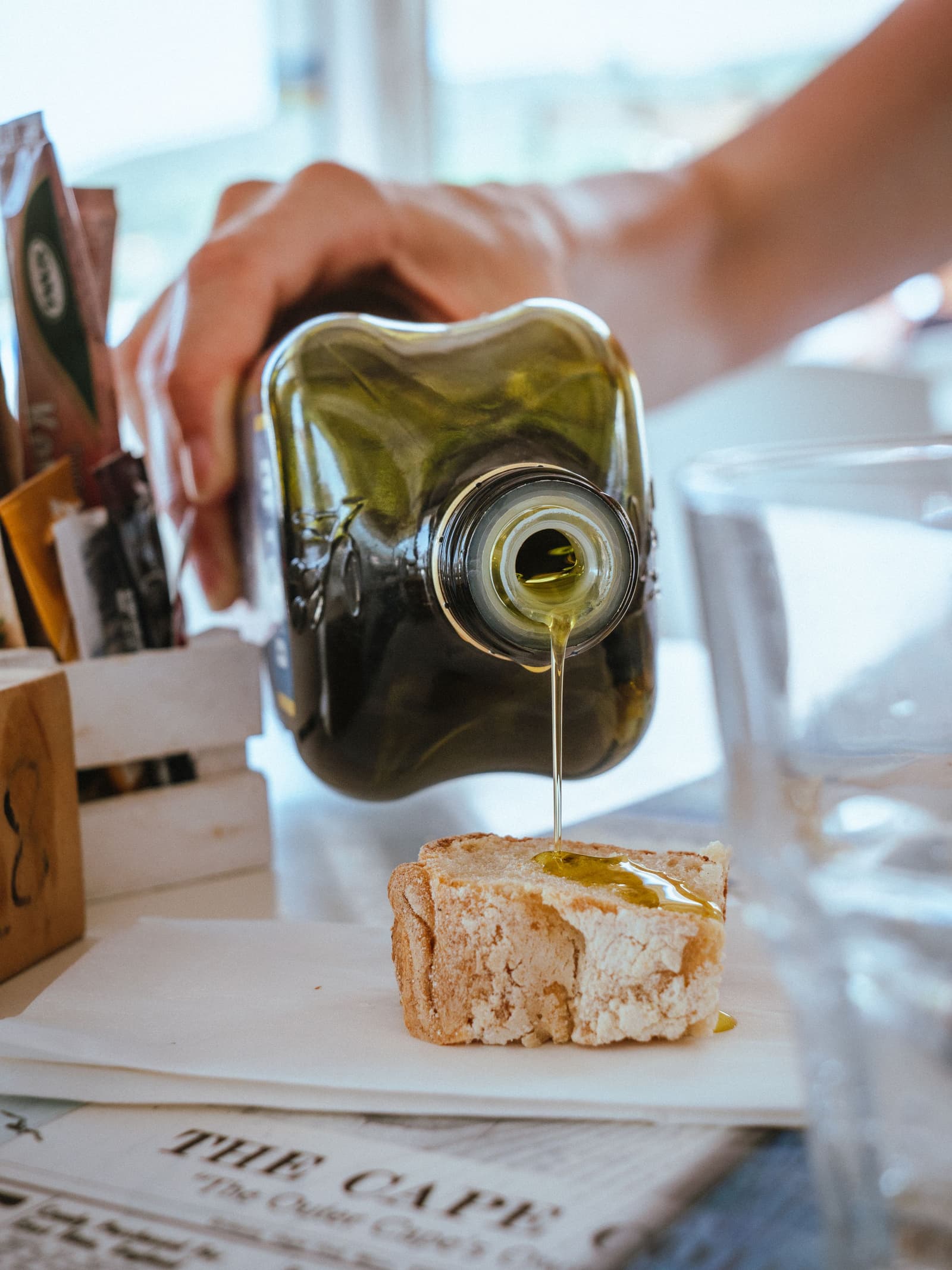 Aceite de oliva virgen extra verde vertiéndose sobre una gruesa rebanada de pan tostado rústico
