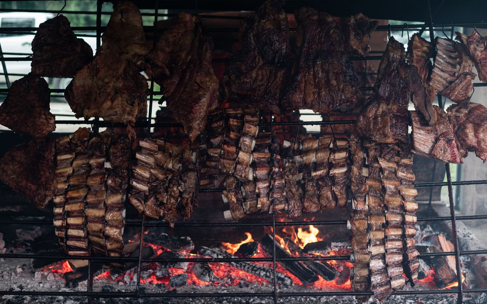 Stukken runderribben grillen boven een open houtvuur