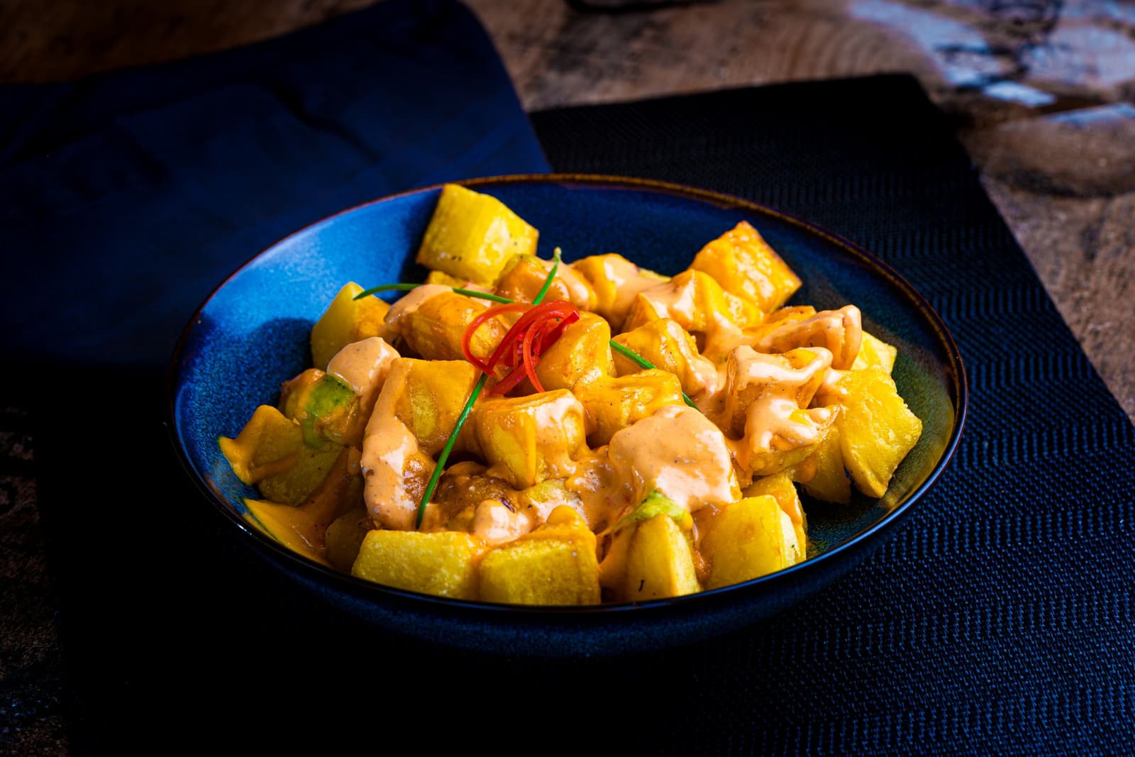 Cubetti di patate fritte con salsa piccante rosa e peperoncino in una ciotola blu