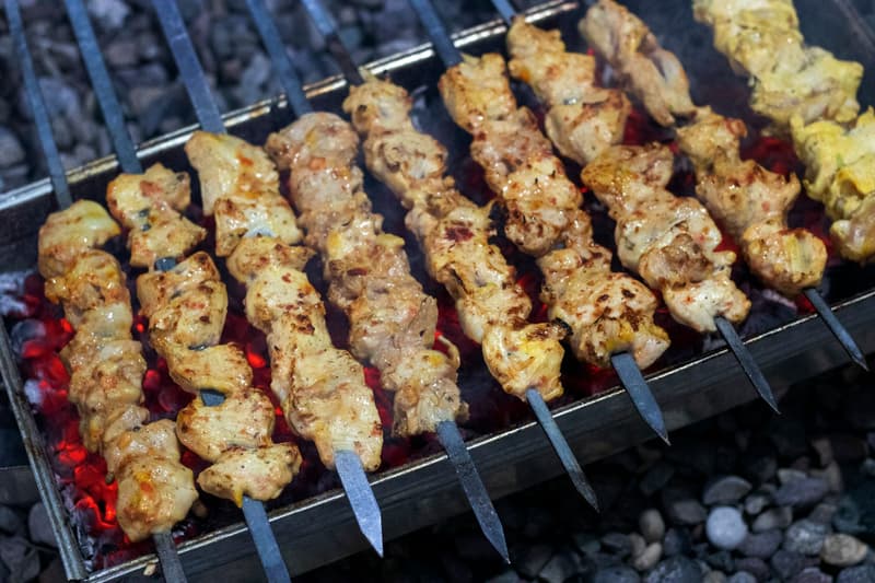 Spiesjes gemarineerde kip die boven gloeiend houtskool grillen