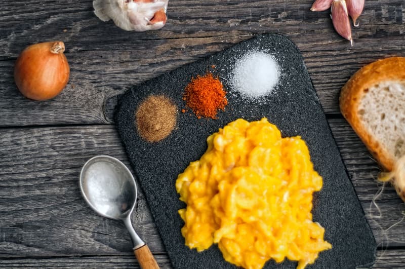 Œufs brouillés crémeux et brillants dressés sur une assiette sombre