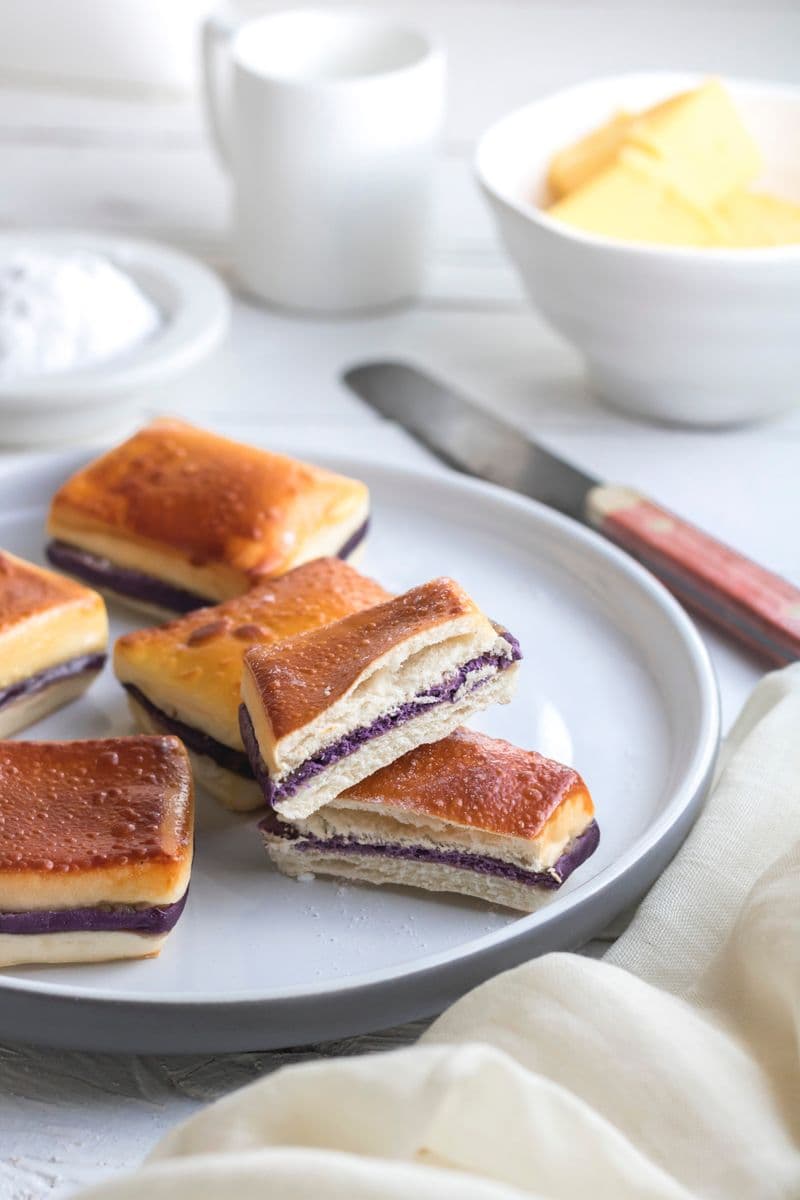 Soft bread rolls filled with vivid purple ube yam paste on a white plate