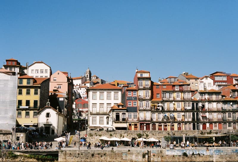 Casas históricas de colores junto al río en el barrio de Ribeira, Oporto, bajo un cielo azul