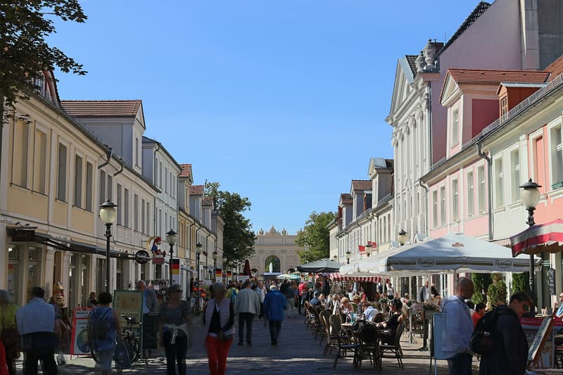 Passanten und Café-Terrassen in der Brandenburger Straße in Potsdam, am Ende ein steinernes Tor