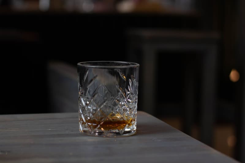 A cut-crystal glass of amber whisky on a dark bar counter