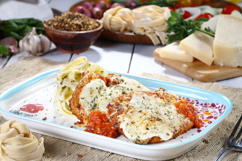 Escalopes de poulet panées recouvertes de fromage fondu et de sauce tomate, servies avec des pâtes