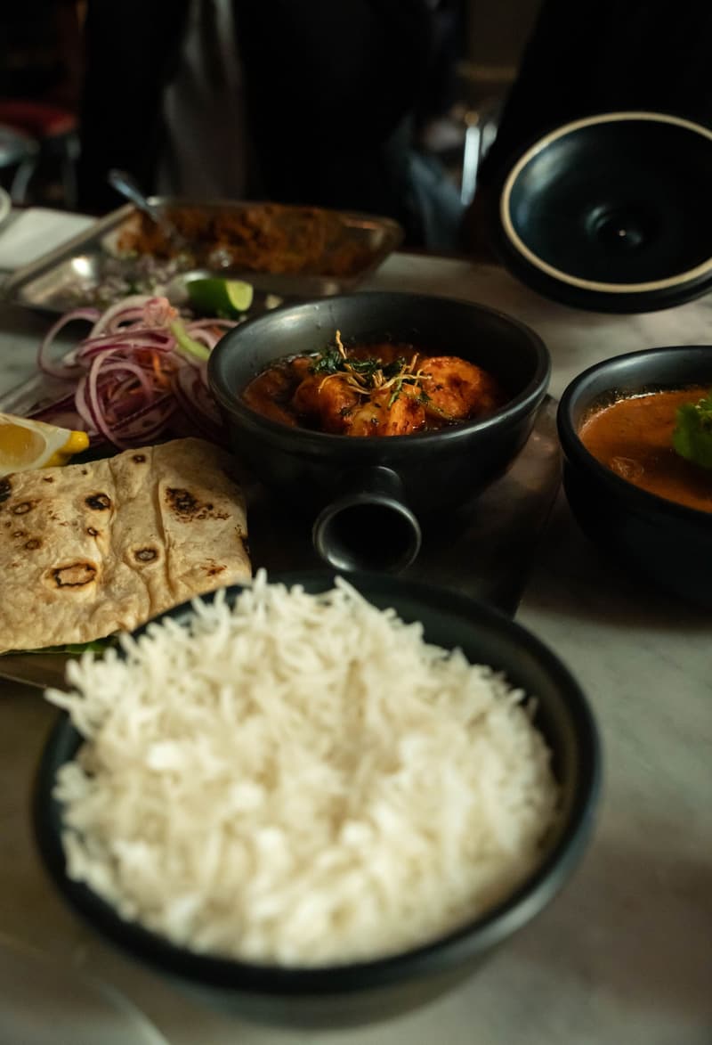 Un assortiment de plats indiens régionaux avec curry, pain plat et riz sur une table de restaurant