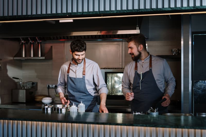 Deux cuisiniers en tablier préparent des plats ensemble dans une cuisine de restaurant