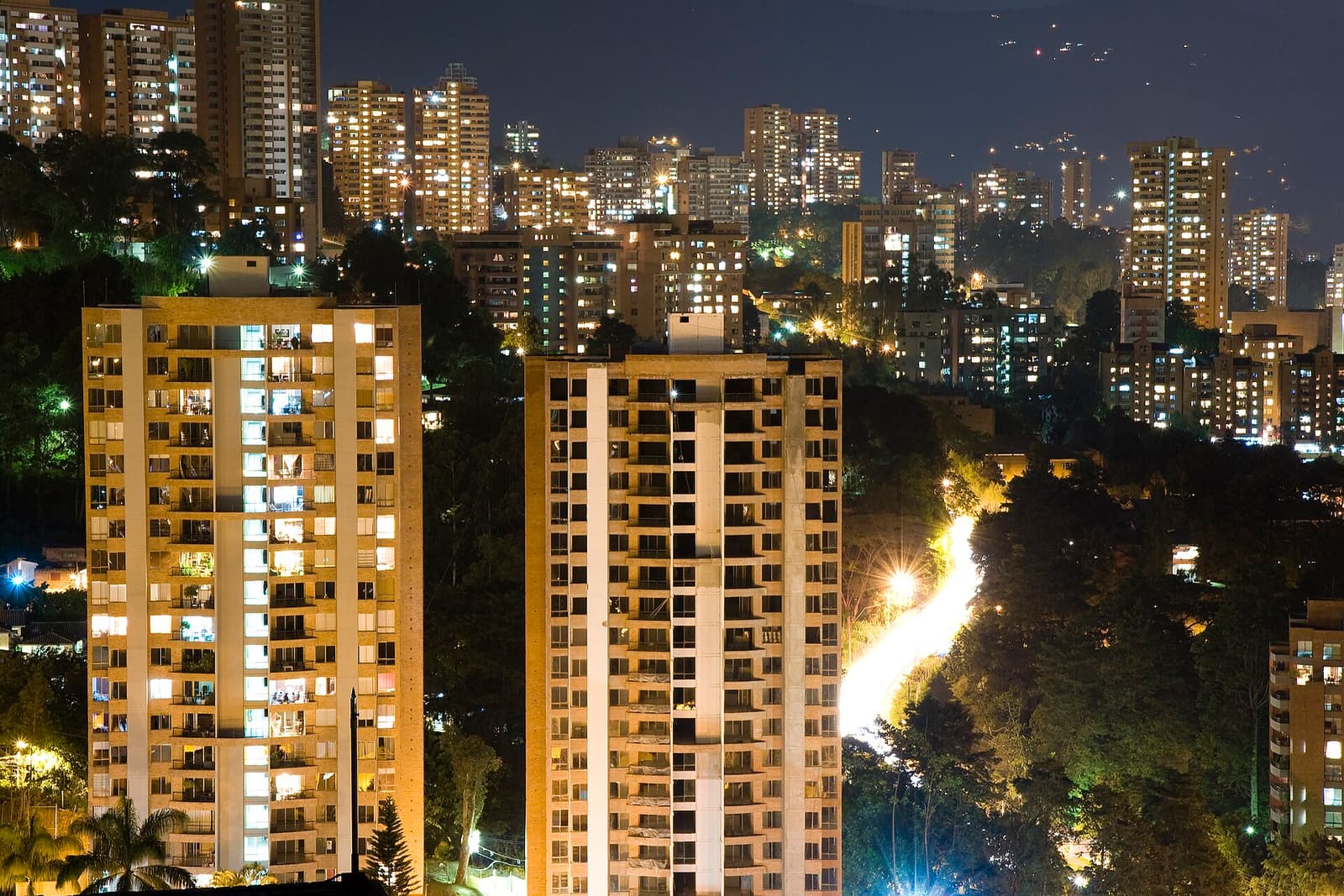 Beleuchtete Wohntürme und eine Hangstraße im Viertel El Poblado in Medellín bei Nacht