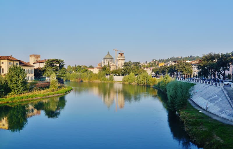 Il fiume Adige a Verona sotto un cielo limpido, con una chiesa a cupola