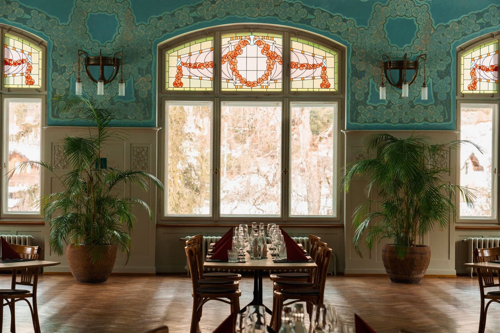 Elegante art-nouveau eetzaal met glas-in-loodramen en palmen
