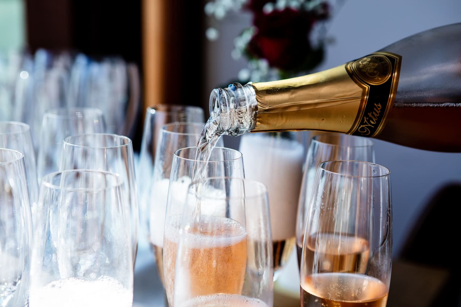 A sommelier in a white jacket pouring champagne into a flute