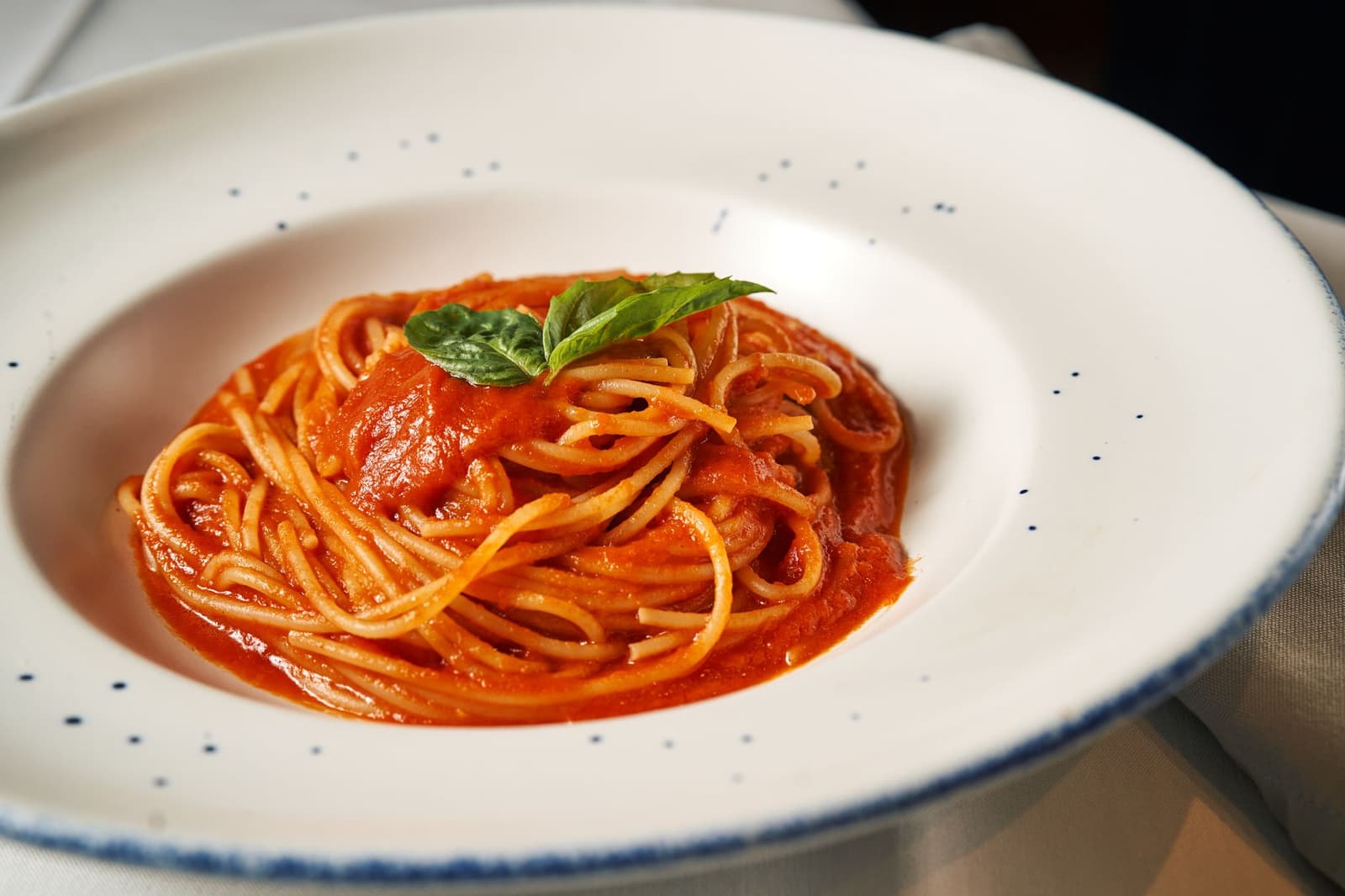 Teller Spaghetti al pomodoro garniert mit frischen Basilikumblättern