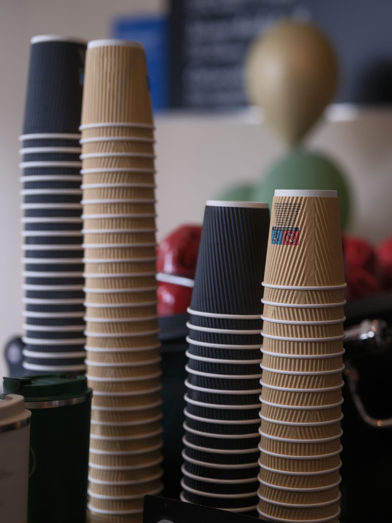 Stacked black and kraft paper takeaway coffee cups on a cafe counter