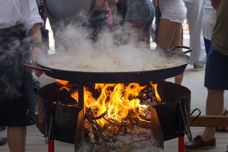 Grande poêle à paella fumante sur un feu de bois lors d'un concours à Sueca