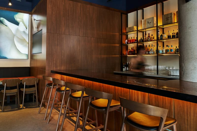 Bar de restaurant en bois vide avec des tabourets et un mur de bouteilles éclairé