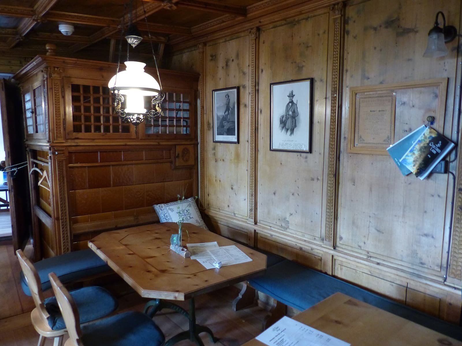 Salle à manger lambrissée de pin d'une auberge de montagne suisse, menus posés sur la table