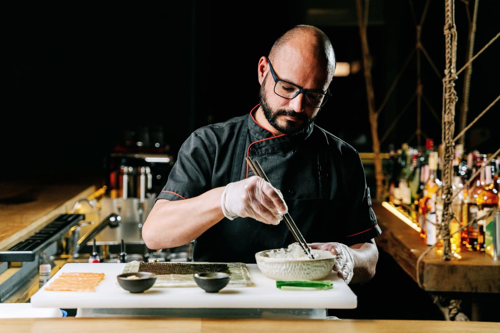 Chef dressant des nigiri sushi aux baguettes sur un comptoir