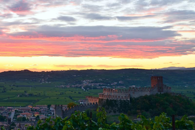 Murallas del castillo de Soave sobre el pueblo y los viñedos de la llanura véneta al atardecer