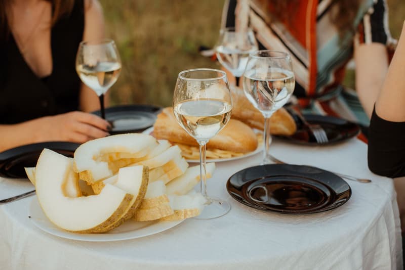 Bancarella di un festival gastronomico all'aperto con calici di vino rosso e un piatto impiattato