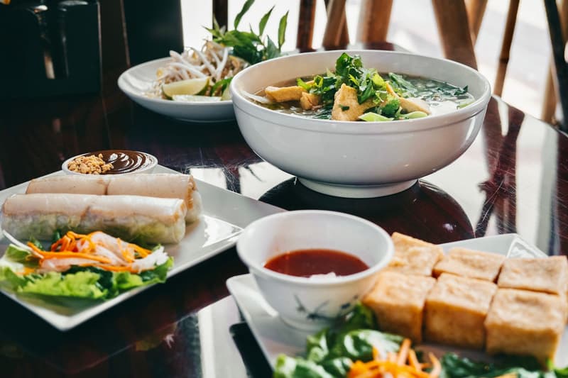 Ciotole di pho vietnamita, involtini primavera e tofu fritto su un tavolo