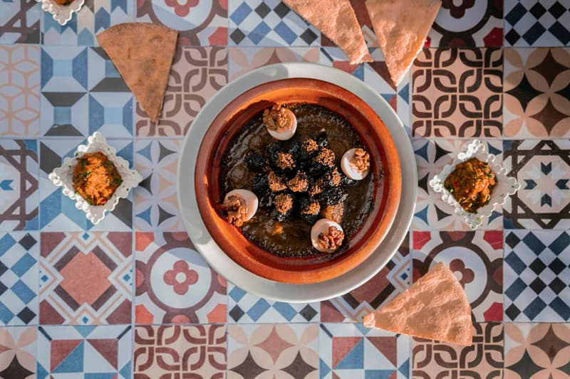 Tajine di agnello con prugne, noci e uova su un tavolo marocchino di piastrelle