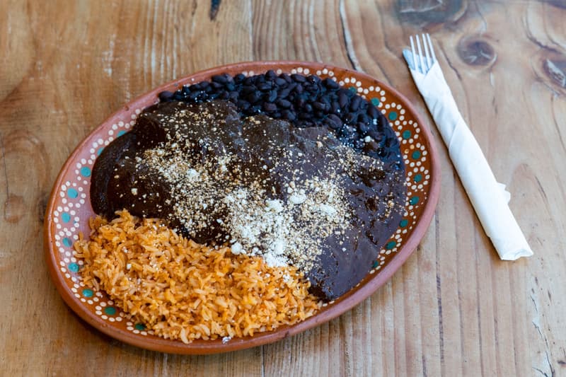 Piatto di mole negro con fagioli neri e riso su ceramica dipinta oaxaqueña