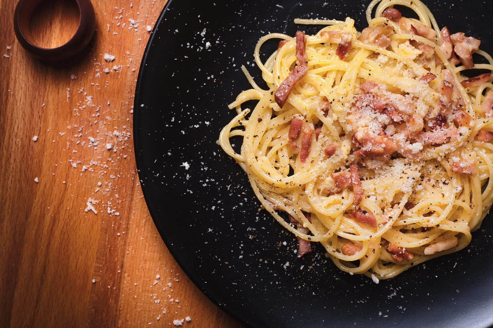Espaguetis a la carbonara con guanciale, pecorino y pimienta negra en un plato oscuro