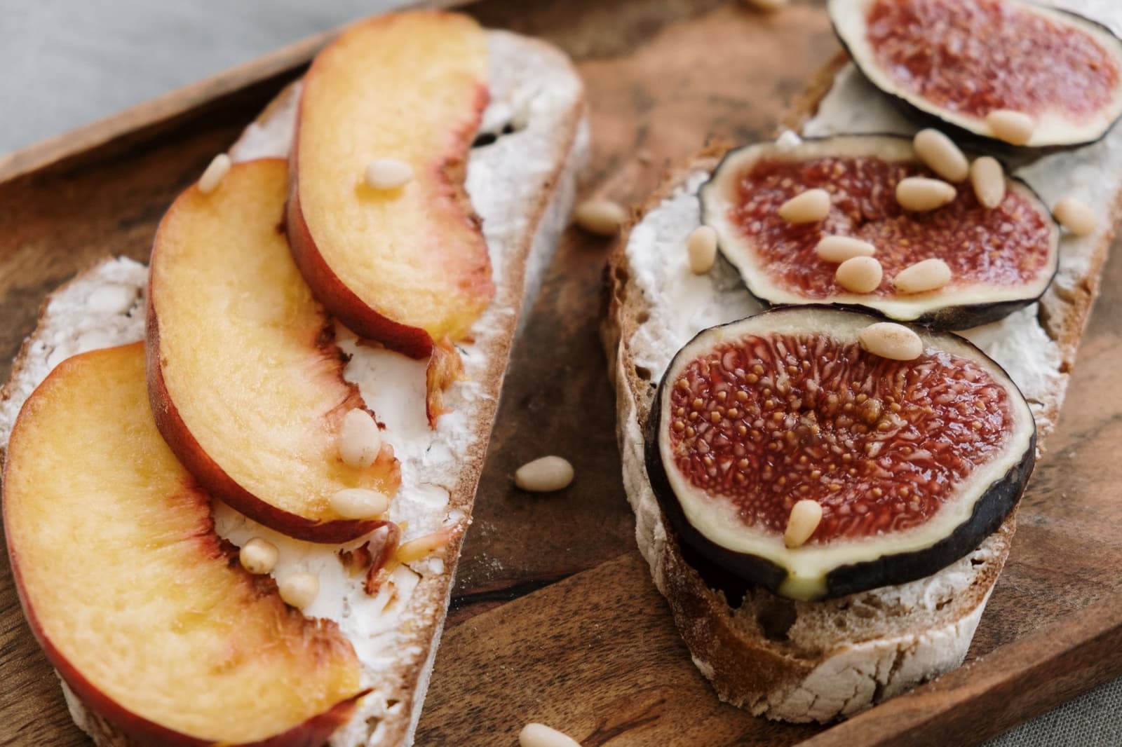 Gegrilltes Brot belegt mit geschlagener Ricotta, frischen Feigen und Pinienkernen