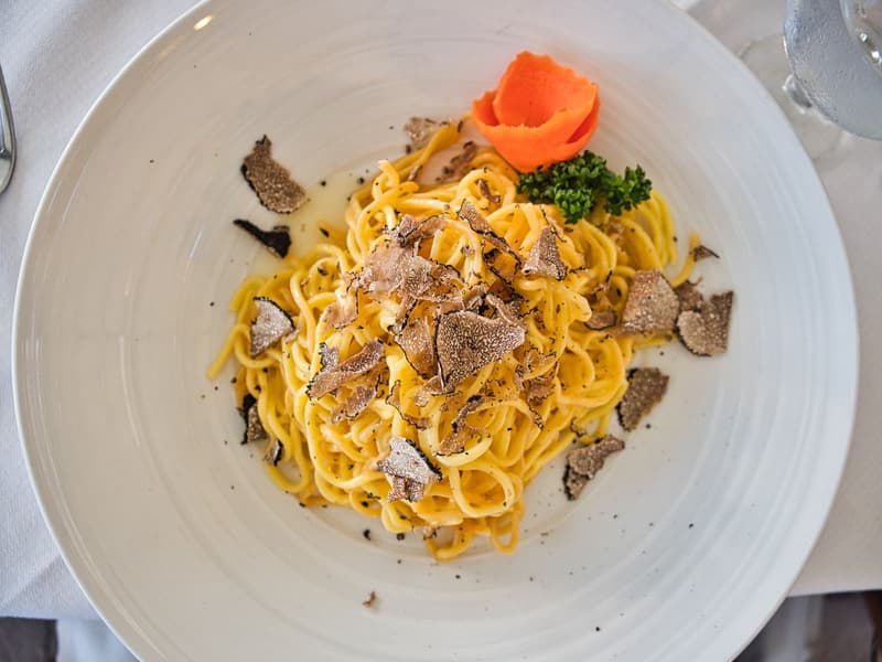 Trufa blanca fresca laminada generosamente sobre un plato de tagliolini