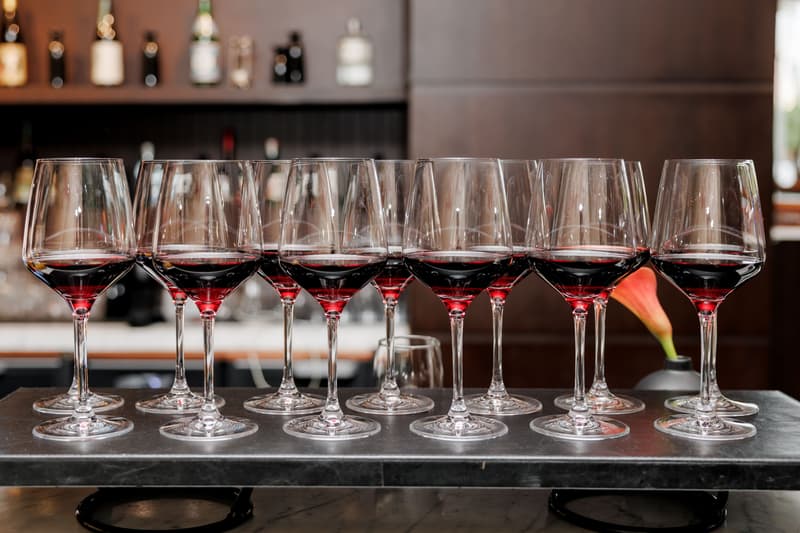 Une rangée de verres à pied remplis de vin rouge alignés sur le bar d'un restaurant