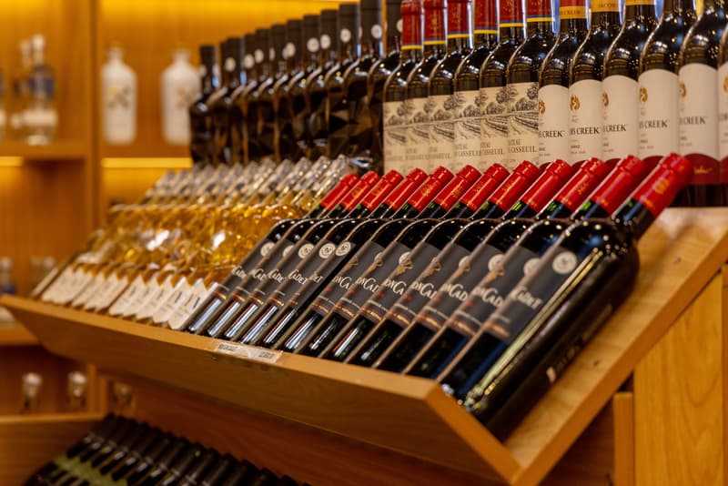 Rows of red and white wine bottles displayed on wooden shop shelving
