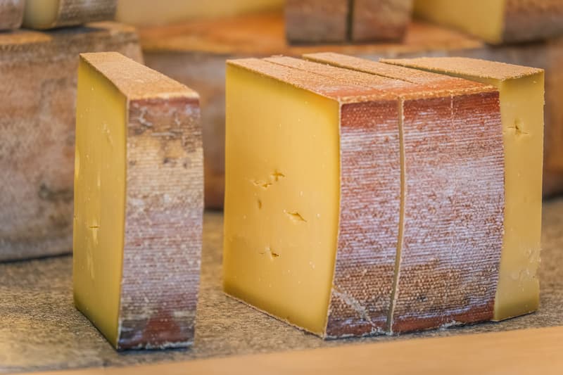 Stücke harten Bergkäses mit gebürsteter Rinde auf einer hölzernen Theke