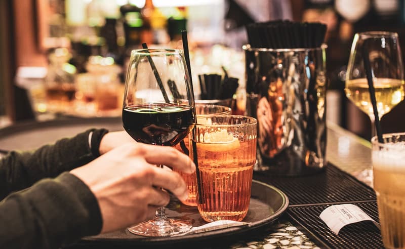 Spritz and wine glasses on a busy Milan bar counter at night