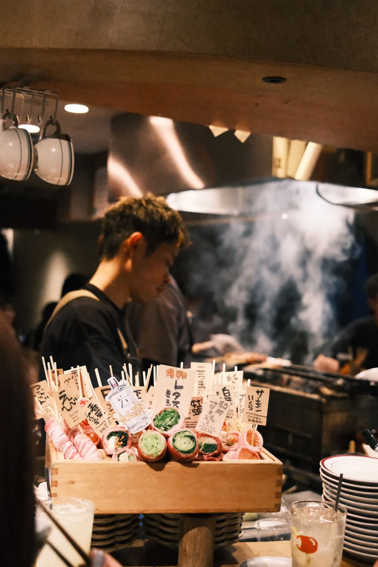 Chef aan de robatagrill achter een toonbank met yakitori-spiesjes in een Japanse izakaya