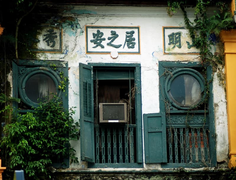 Weathered shophouse facade with green shutters and round windows on Mohamed Sultan Road, Singapore