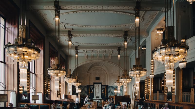 Opulent Art Deco dining room with brass chandeliers and marble columns in a grand European café
